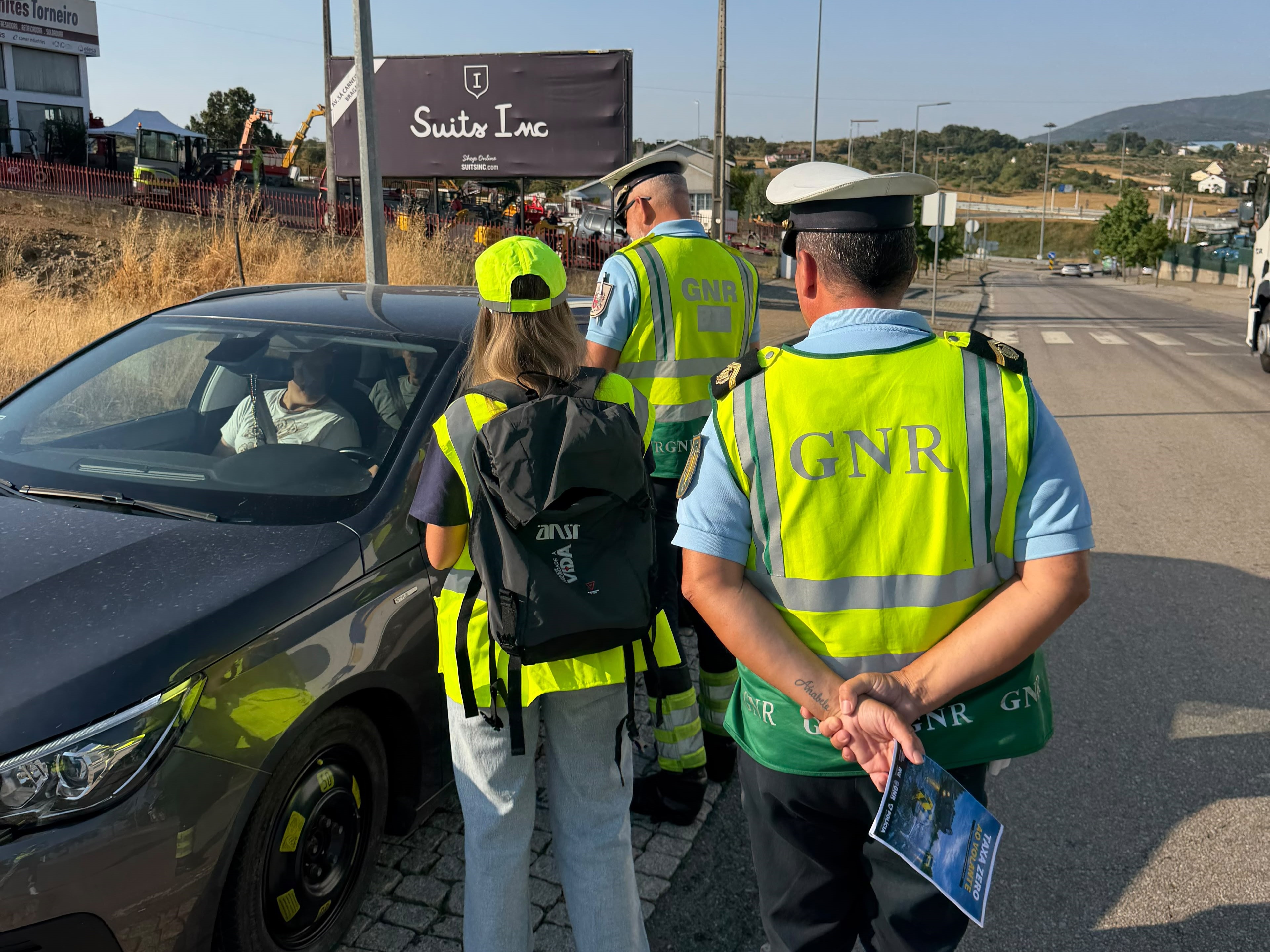 Dois agentes da Guarda Nacional Republicana (GNR), com coletes refletores, abordam um autom&oacute;vel numa estrada, em conjunto com um elemento da ANSR. 